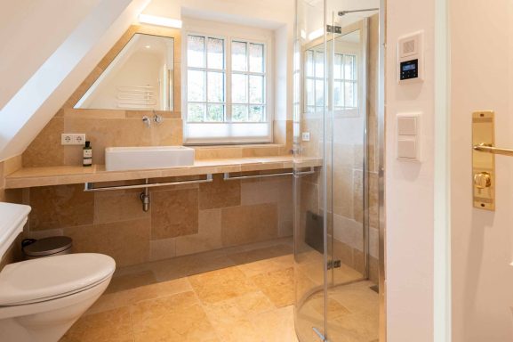 Im Badezimmer mit WC ist geradezu der Waschtisch und rechts die Dusche
