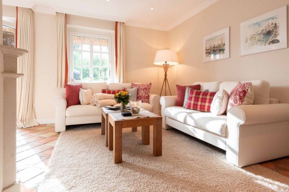 Im Wohnzimmer stehen im Eck zwei Sofa und davor ein Sofatisch mit Blumen